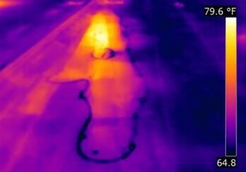 Thermal image showing heat distribution on a paved surface with a bright hot spot.